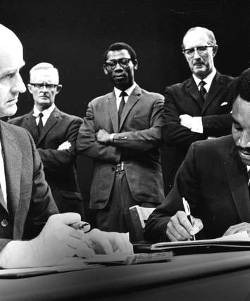 Hero signs document in scene from play The Ladder
