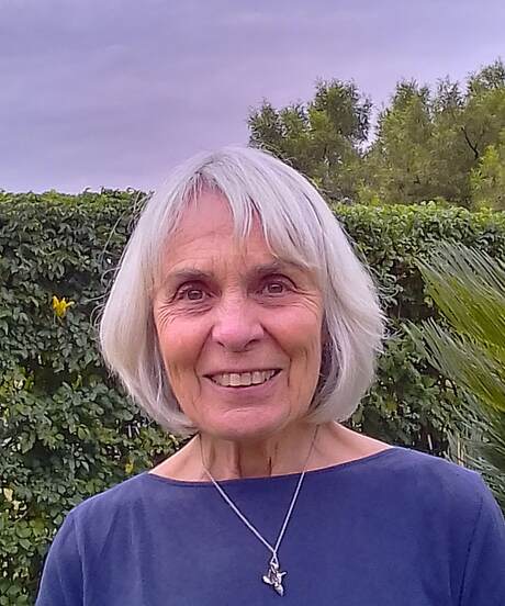 Photo of Suzan Burrell standing in front of a hedge
